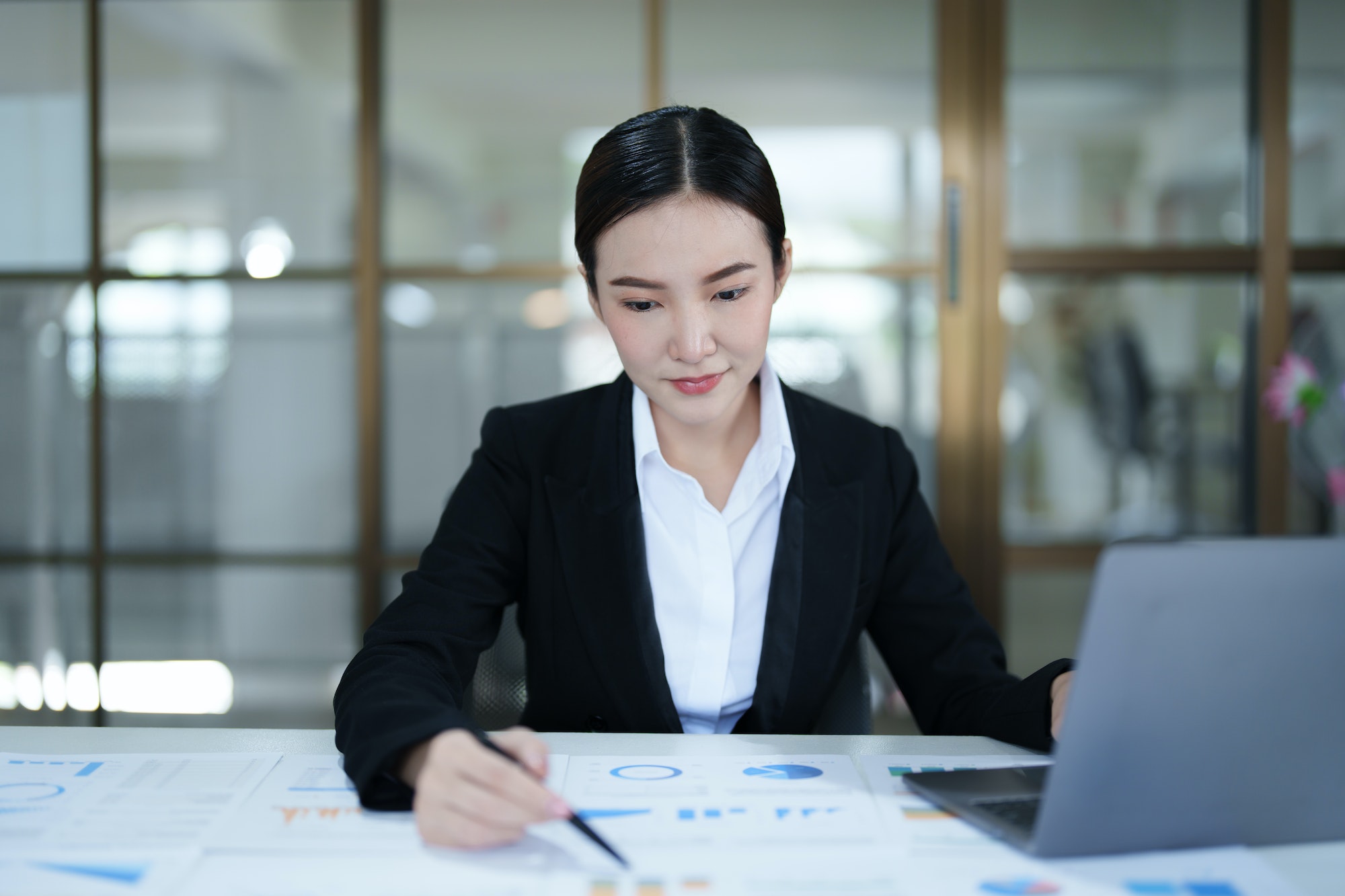 Portrait of a thoughtful Asian businesswoman looking at financial statements and making marketing