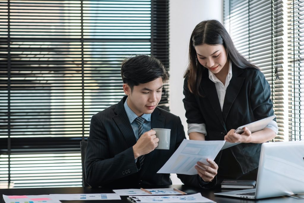 Two Asian business people consultants, work in office and drink coffee.