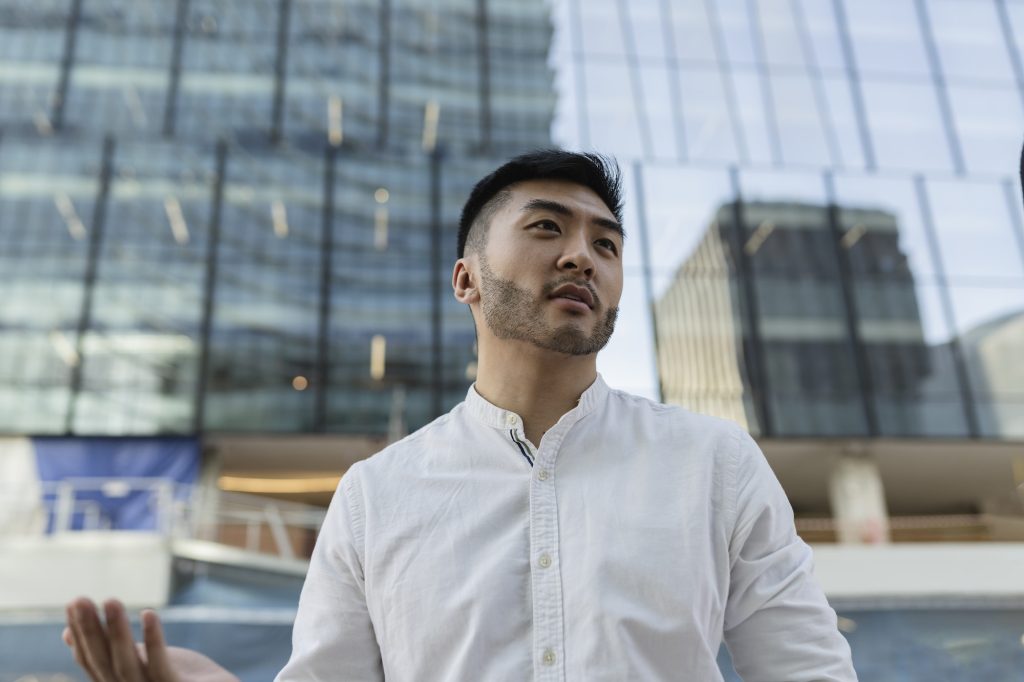 young asian business man professional standing against contemporary financial