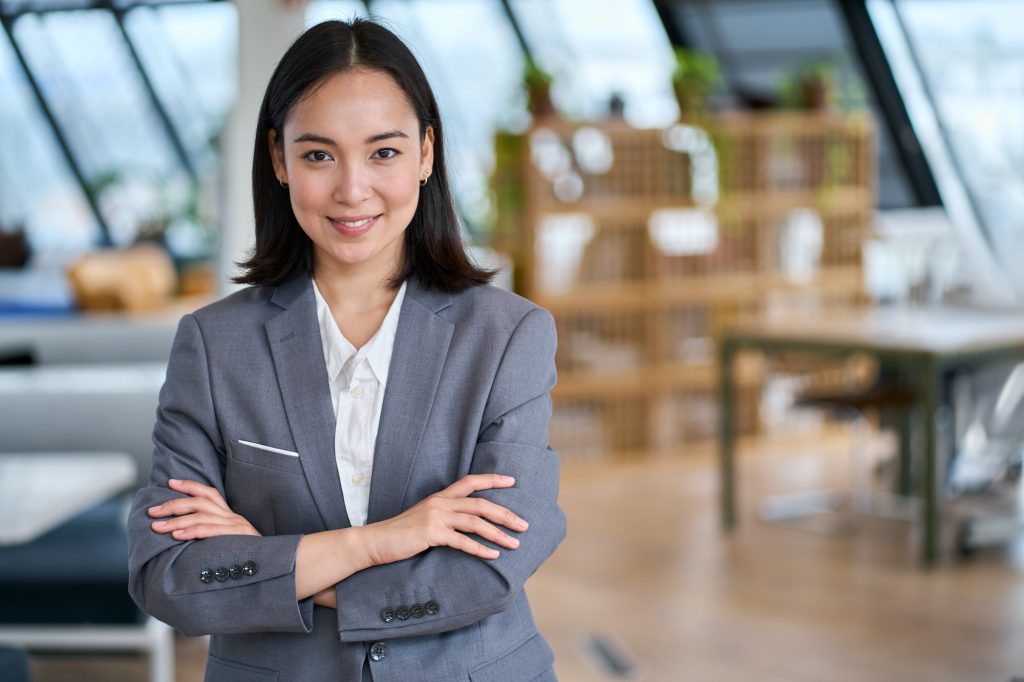 Young confident Asian business woman leader standing in office, portrait.